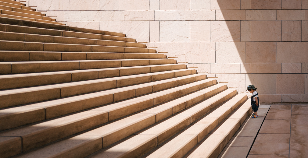 Kleiner Junge steht vor großer Treppe
